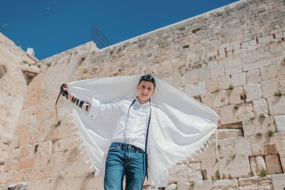 נער אוחז בטלית מול הכותל ונוף ירושלים