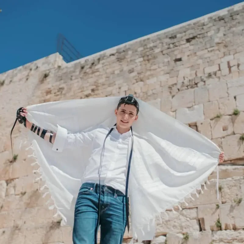 נער אוחז בטלית מול הכותל ונוף ירושלים